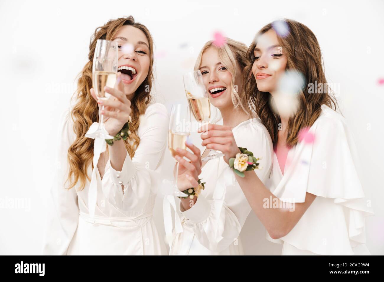 Foto di bridesmaid eccitati e bridesmaid che ridono e bevono champagne isolato su pareti bianche Foto Stock