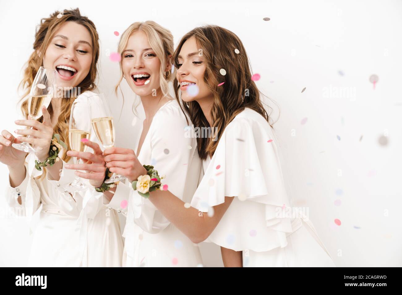 Foto di bridesmaid eccitati e bridesmaid che ridono e bevono champagne isolato su pareti bianche Foto Stock