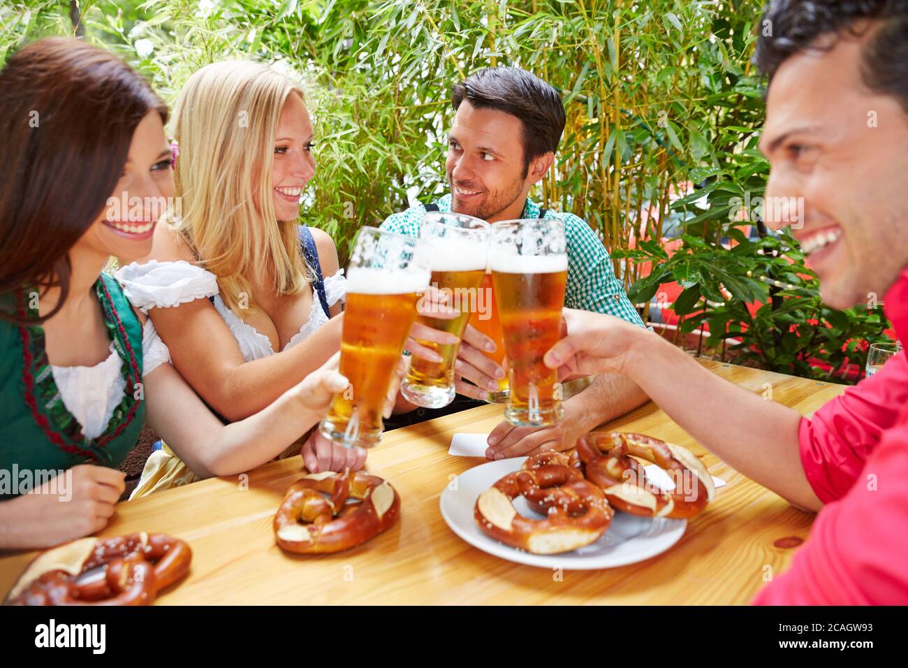 Amici felici nella birreria all'aperto con abiti tradizionali bavaresi che bevono birra insieme Foto Stock