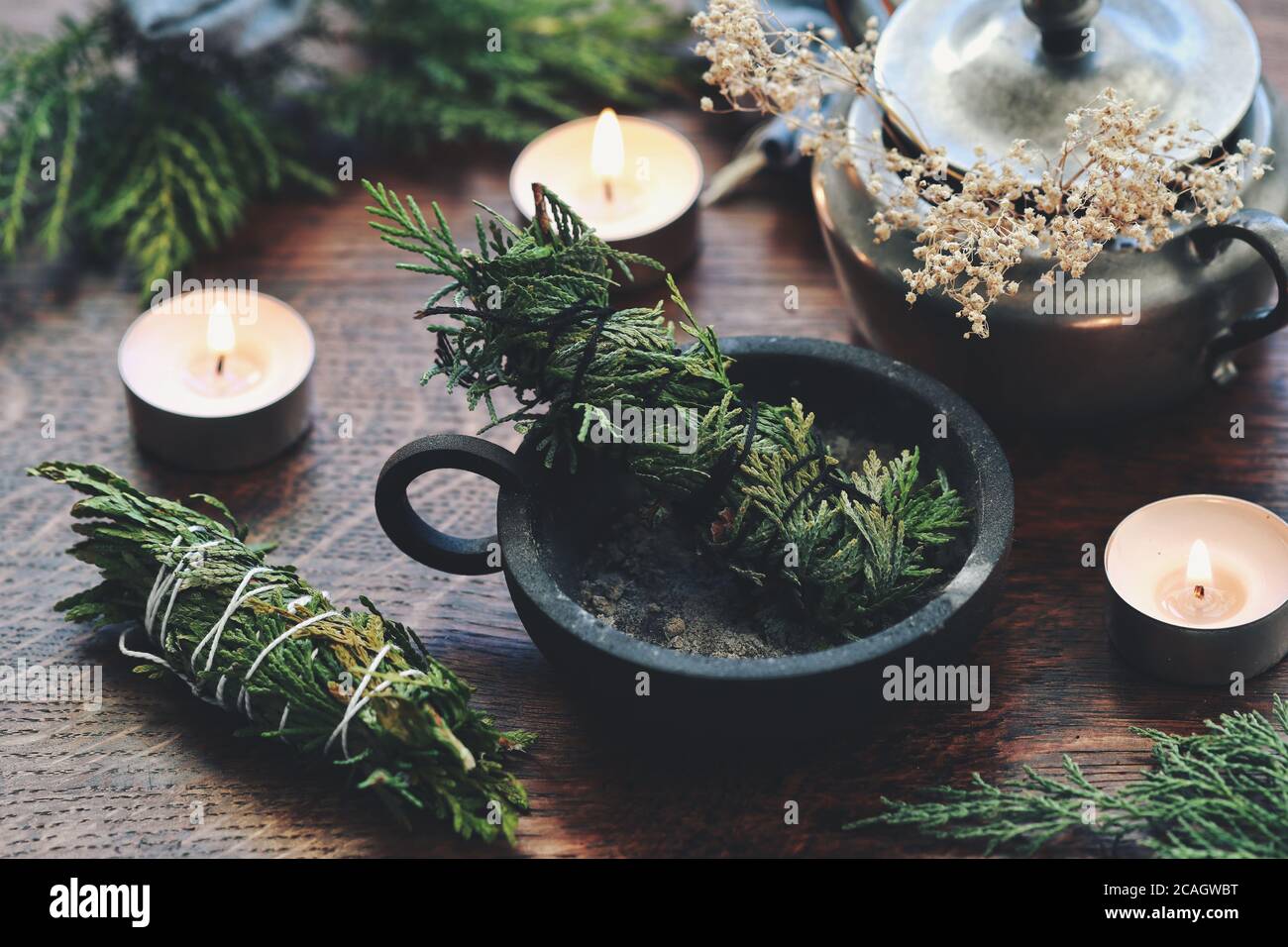 Cedar bastone di pulizia del fumo fatto a mano in ferro di ghisa porta cenere bruciatore su un altare wiccan strega. I fasci di cedro per la pulizia di energia, alternativa al salvia Foto Stock