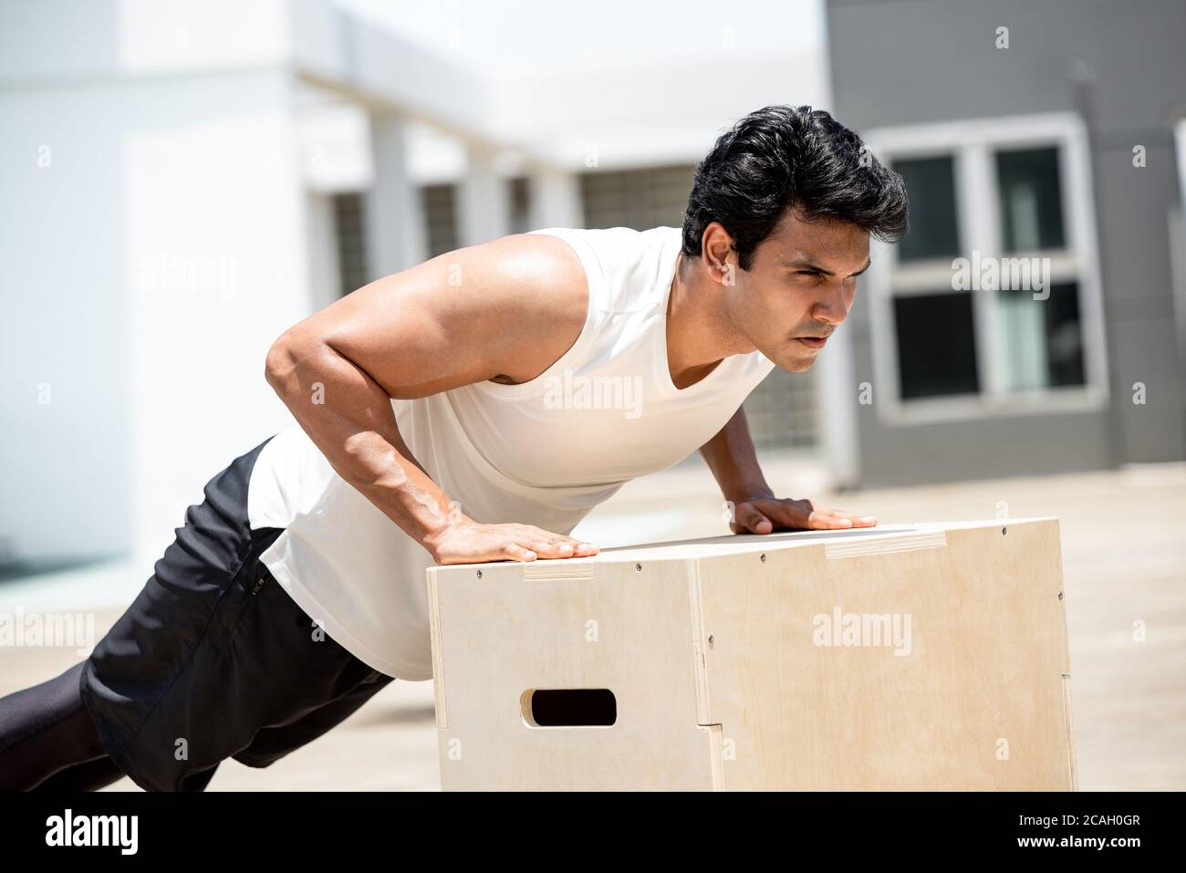 Bell'uomo sportivo indiano che fa esercitare spinta in su all'aperto sul tetto della costruzione, concetto domestico di workout Foto Stock