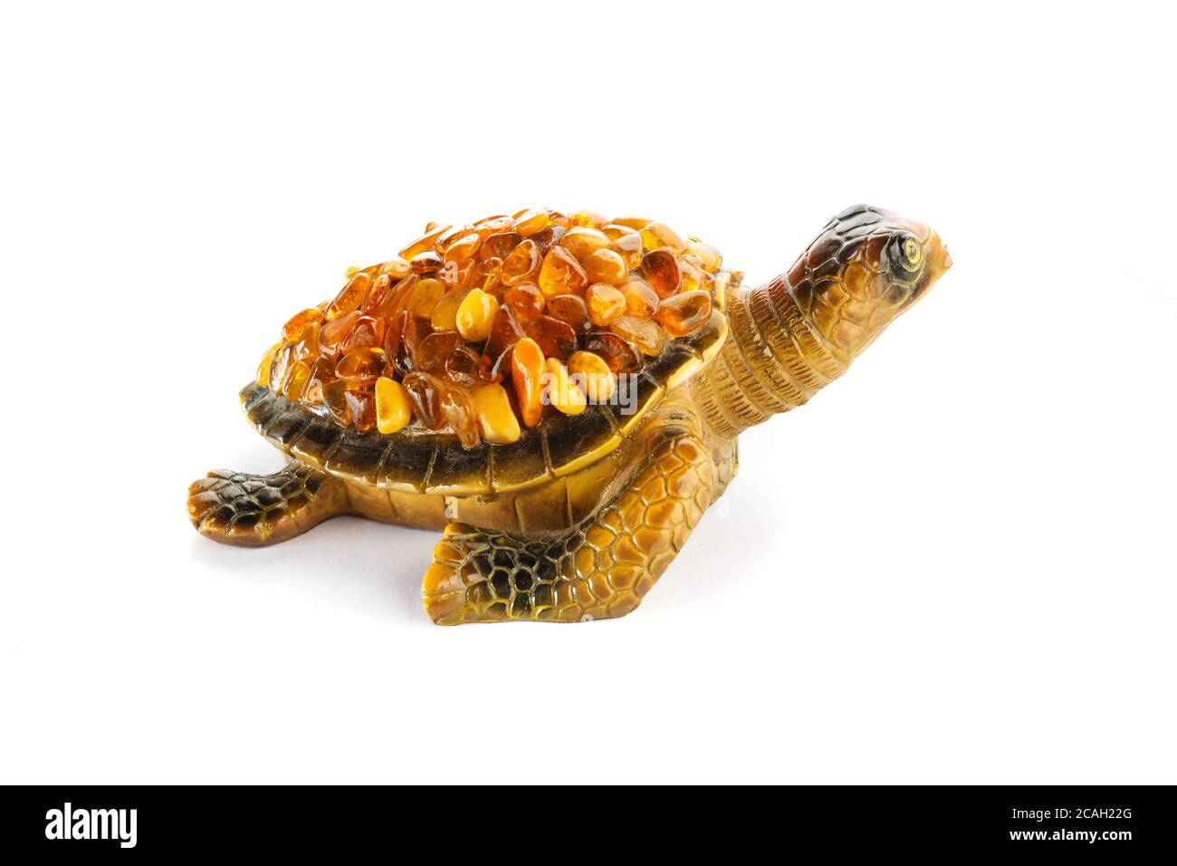 Figura di una tartaruga su sfondo bianco con pietre ambra sulla conchiglia. Foto Stock