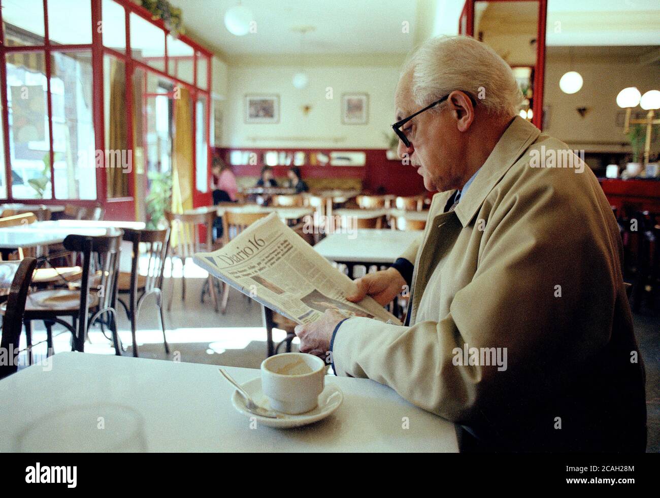 Uomo anziano che legge giornale in un caffè. Foto Stock
