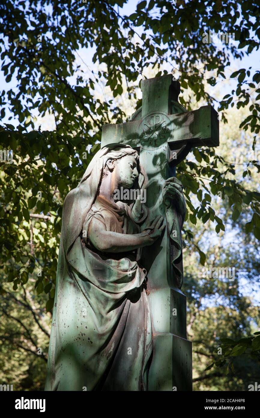 Statua della Vergine Maria con croce su una vecchia tomba al cimitero di Melaten, Colonia, Germania. Marienfigurur mit Kreuz auf einem alten Grab auf dem Me Foto Stock