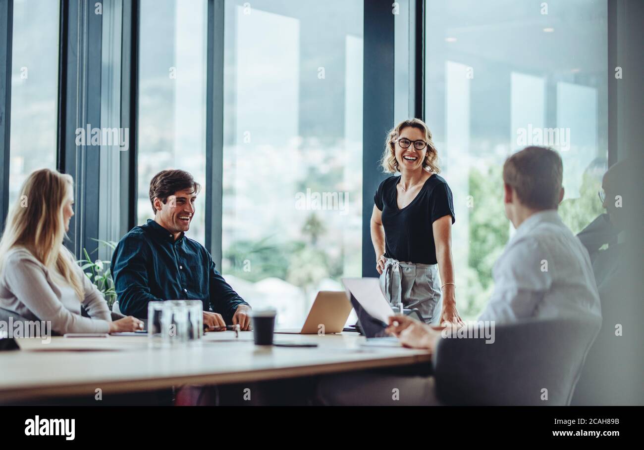 I colleghi di ufficio hanno una discussione informale durante la riunione nella sala conferenze. Gruppo di uomini e donne seduti nella sala conferenze e sorridenti. Foto Stock