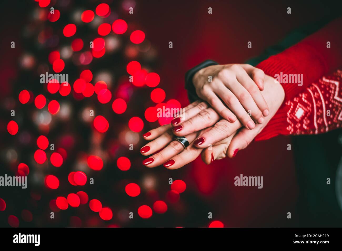 Mani di una coppia appena sposata. Su sfondo rosso, illuminazione Foto Stock