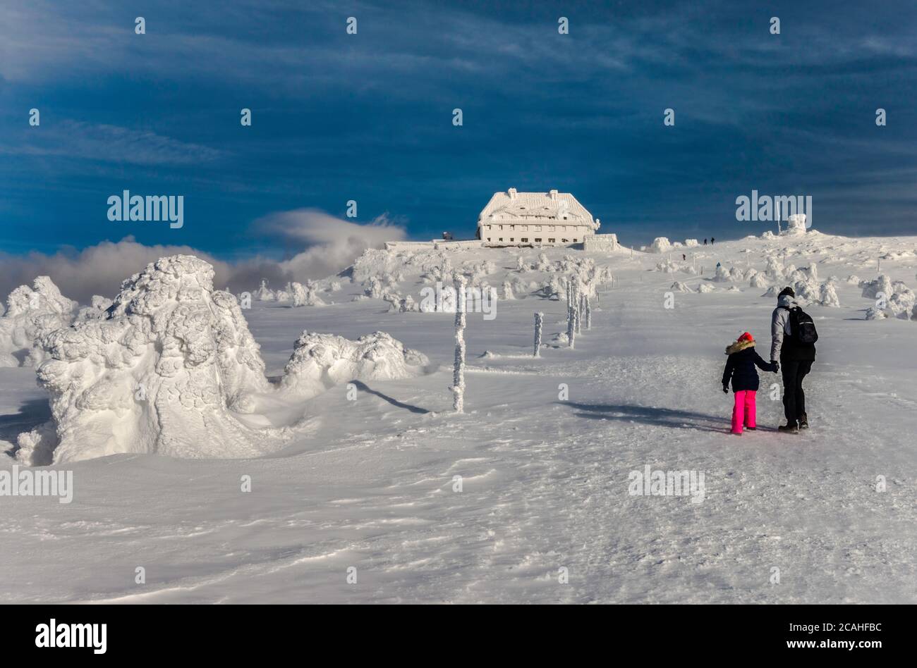 Escursione con genitori e bambini in forte vento in inverno a Graniczna Łąka (Prato di confine) vicino al rifugio a Szrenica, Parco Nazionale di Karkonosze, Polonia/Czechia Foto Stock