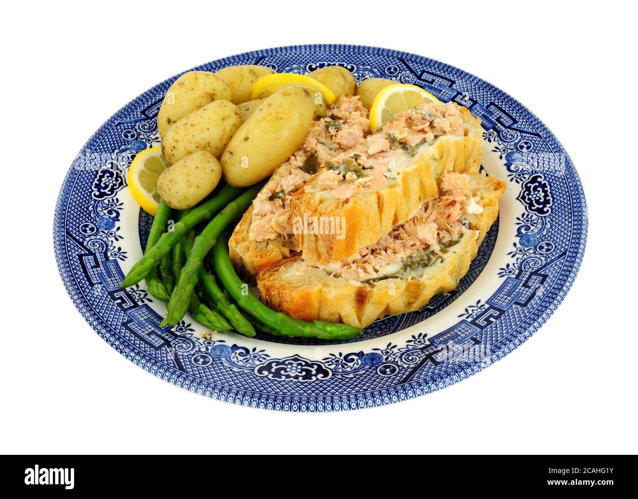 Pasta sfoglia tagliata al salmone coperto Wellington pasto con patate novelle e asparagi isolati su sfondo bianco Foto Stock
