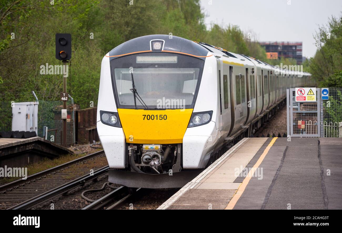 Treno passeggeri di classe 700 a Thameslink livrea in avvicinamento ad una stazione ferroviaria, Inghilterra. Foto Stock