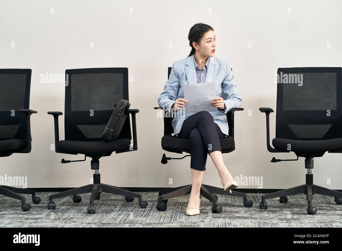 giovane cercatore di lavoro femminile asiatico seduto in sedia ansiosamente in attesa di intervista Foto Stock