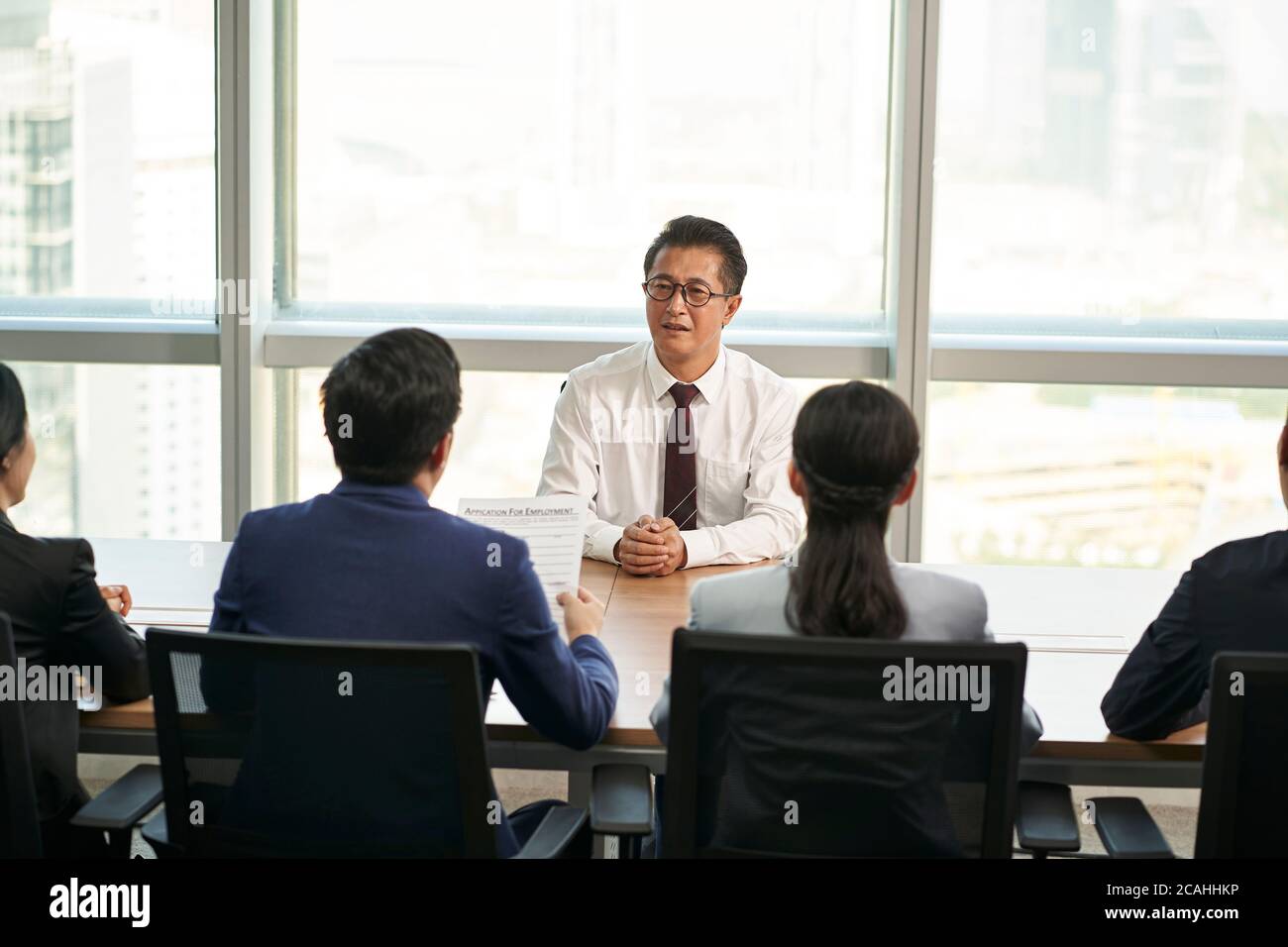 il cercatore di lavoro dell'uomo d'affari asiatico più anziano è intervistato da un gruppo di giovani dirigenti delle risorse umane Foto Stock