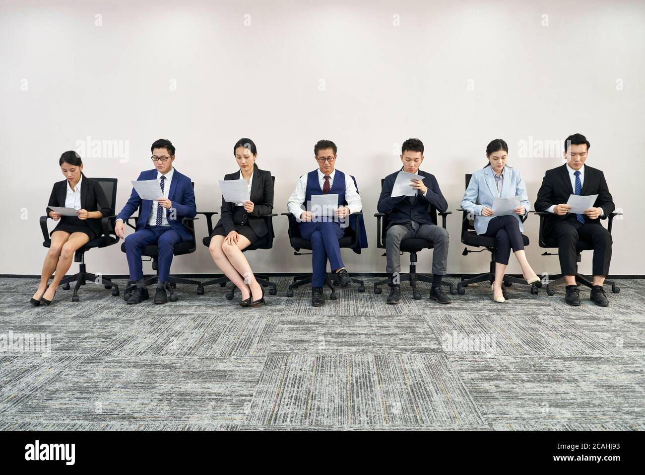 gruppo di uomini e donne d'affari asiatici in attesa di colloquio di lavoro in linea Foto Stock