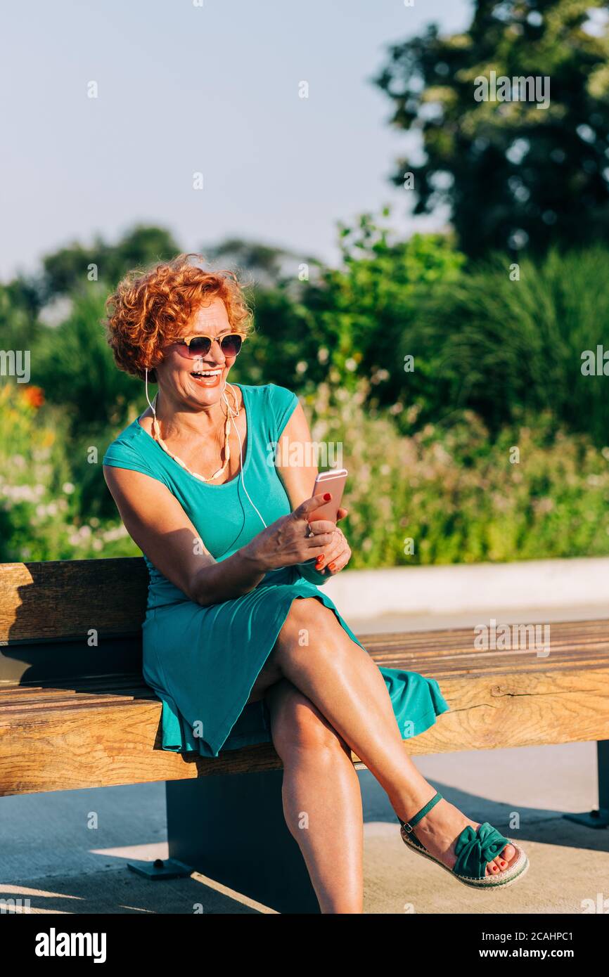 Donna matura che ascolta la musica sul suo smartphone in il parco Foto Stock