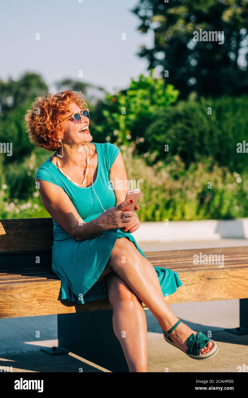 Donna matura che ascolta la musica sul suo smartphone in il parco Foto Stock