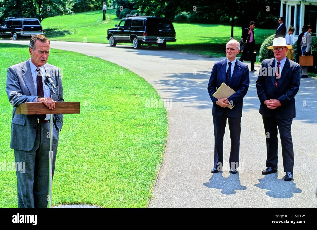 In questa foto, il presidente degli Stati Uniti George H.W. Bush parla ai giornalisti dell'invasione irachena del Kuwait prima di lasciare la Casa Bianca per il ritiro presidenziale a Camp David il 3 agosto 1990. A destra sono il consulente nazionale di sicurezza Brent Scowcroft e il segretario della Casa Bianca Marlin Fitzwater (indossare cappello).Credit: Ron Sachs / CNP / MediaPunch Foto Stock