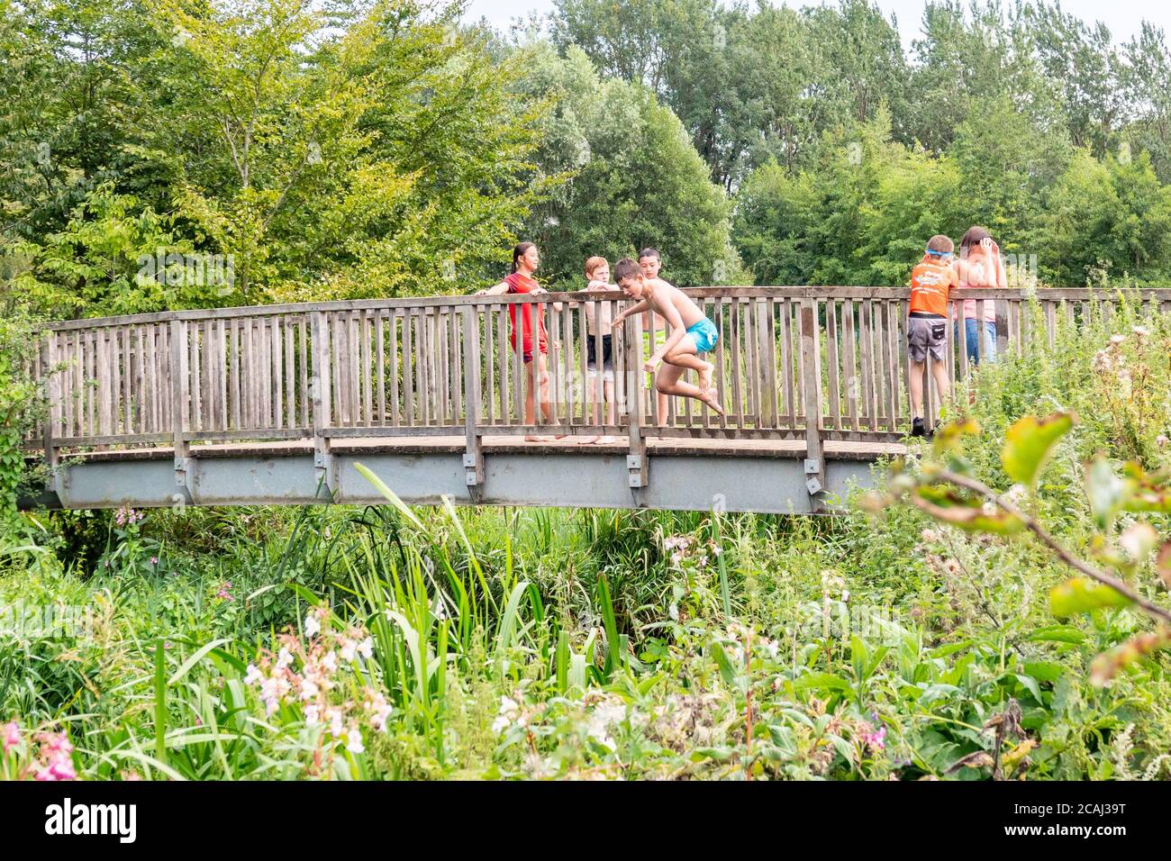 Henlow, Bedfordshire, Regno Unito. 7 agosto 2020. Mentre le temperature saliranno, i bambini locali potranno rinfrescarsi nel fiume Ivel accanto al Millennium Meadow di Henlow. Bambini in vacanza scolastica che salgono in acqua da un ponte di legno. Foto Stock
