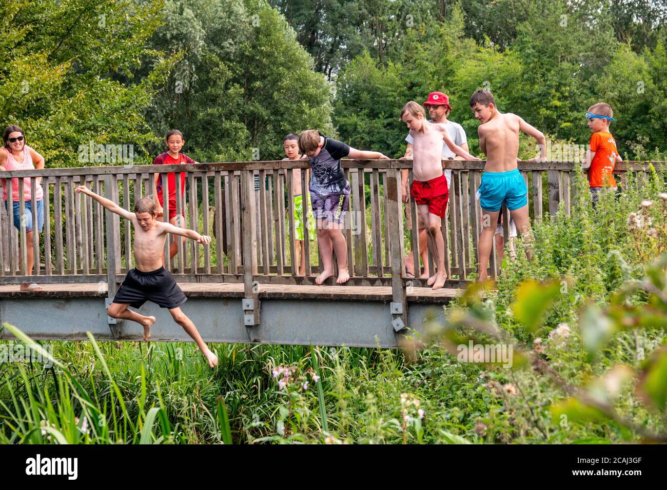 Henlow, Bedfordshire, Regno Unito. 7 agosto 2020. Mentre le temperature saliranno, i bambini locali potranno rinfrescarsi nel fiume Ivel accanto al Millennium Meadow di Henlow. Bambini in vacanza scolastica che salgono in acqua da un ponte di legno. Foto Stock