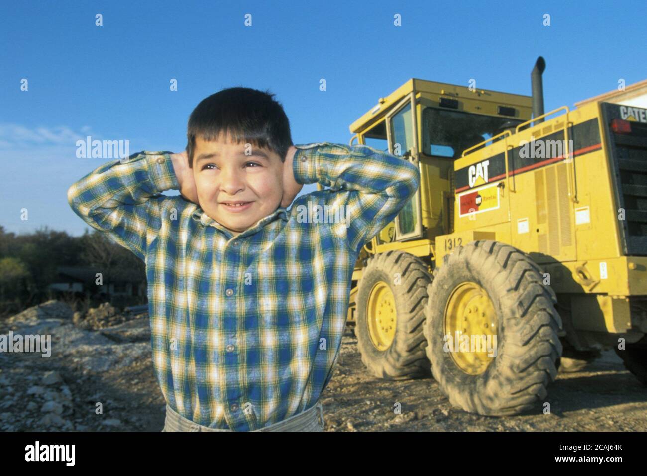 Giovane ragazzo nativo americano che copre le orecchie con le mani per bloccare il forte rumore della costruzione. Versione modello ©Bob Daemmrich Foto Stock