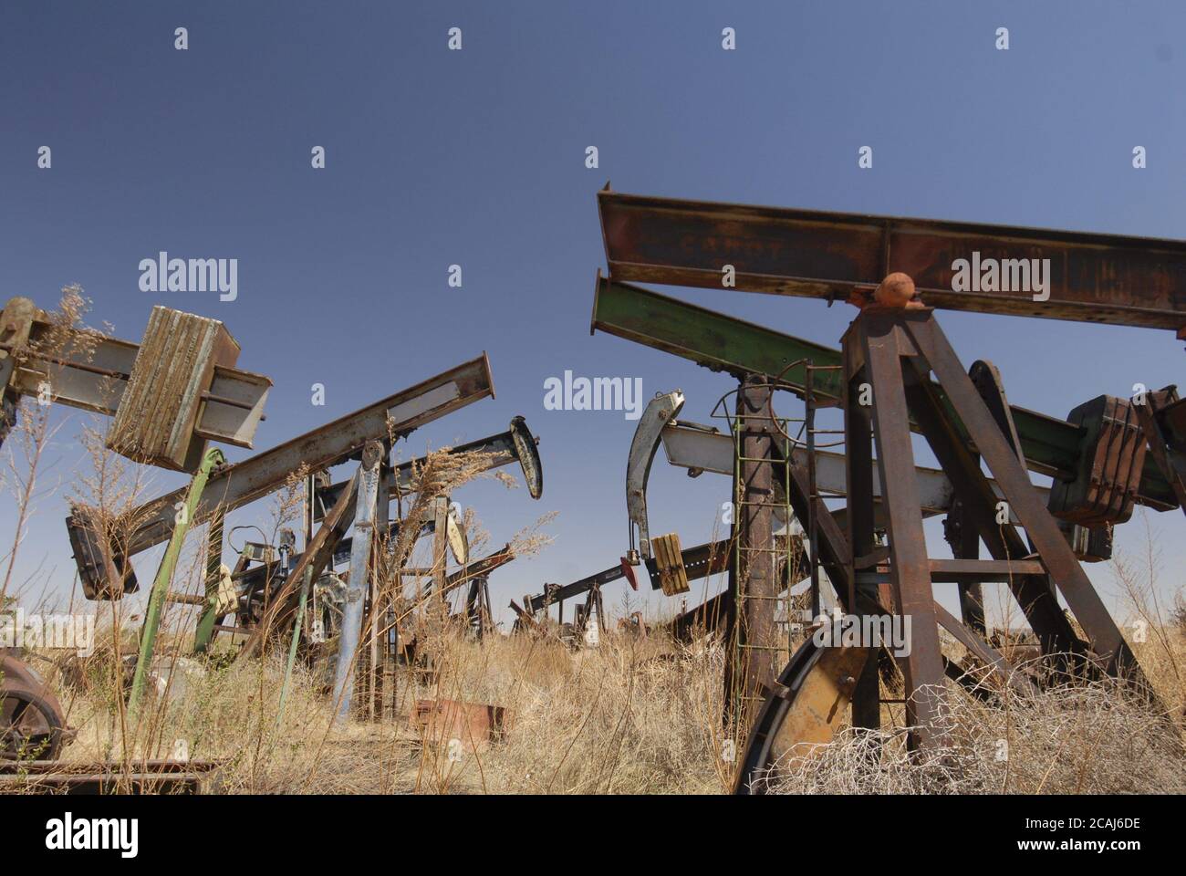 McCamey, TX Marzo, 2006: Gli scricchiolii arrugginiti delle attrezzature di pompaggio del pozzo del petrolio siedono che allontano l'autostrada US 67 nella contea di Upton, TX dove le fattorie eoliche hanno sostituito i pozzi del petrolio come la nuova economia del Texas occidentale asciutto. Foto di Bob Daemmrich ©Bob Daemmrich Foto Stock