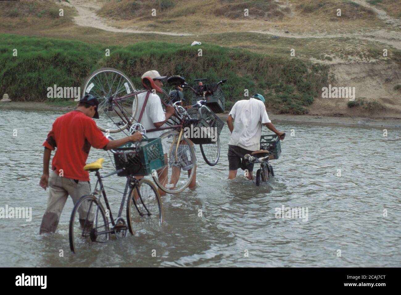 Gruppo di messicani con biciclette che attraversano un punto poco profondo nel fiume Rio grande, il confine tra Stati Uniti e Messico, vicino a Brownsville, Texas. ©Bob Daemmrich Foto Stock