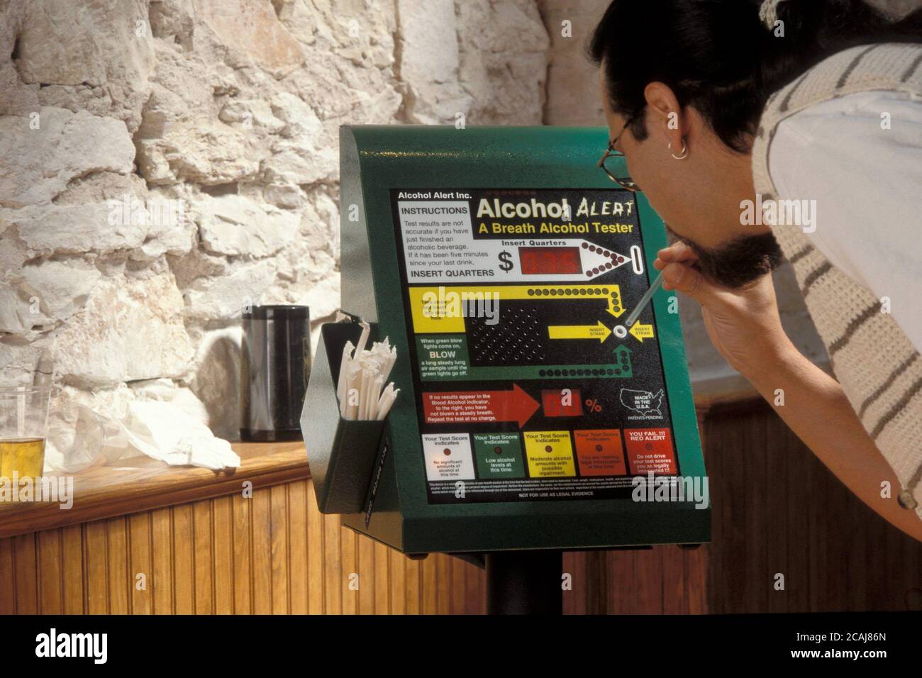 Uomo ispanico che esamina il livello di alcol nel sangue soffiando in una macchina a gettoni in un bar ad Austin, Texas. Versione del modello. ©Bob Daemmrich Foto Stock
