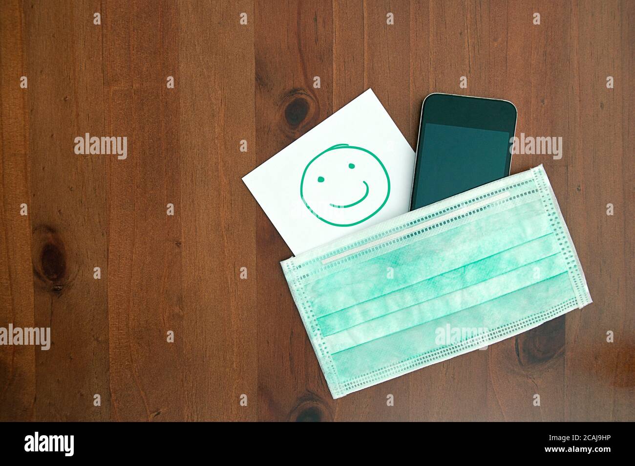 healthcare hygienic mask smartphone smile paper wooden background Foto Stock
