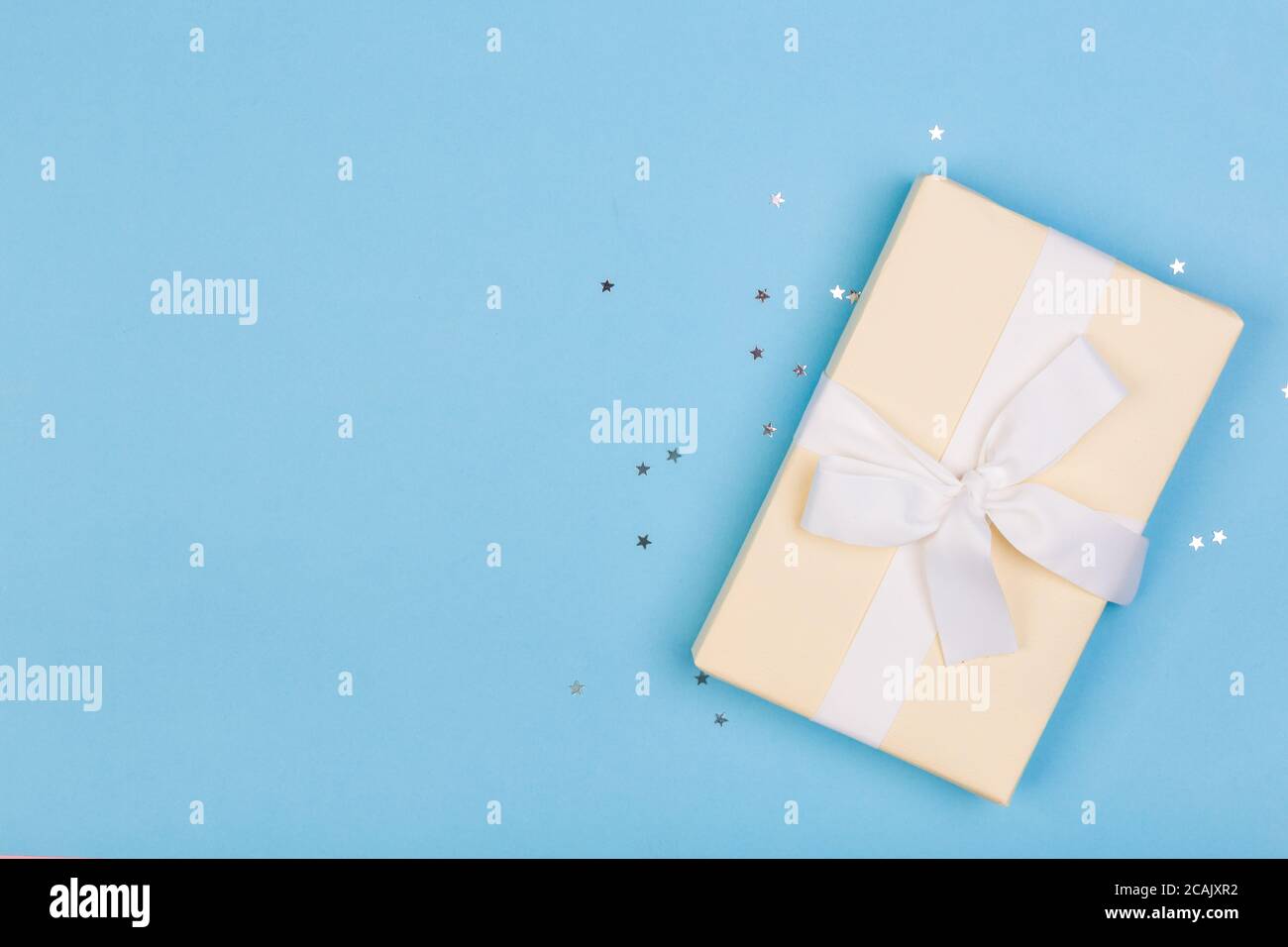 Confezione regalo o regalo e stelle confetti su un tavolo blu dall'alto. Composizione piatta per compleanno, giorno delle madri o matrimonio. Foto Stock