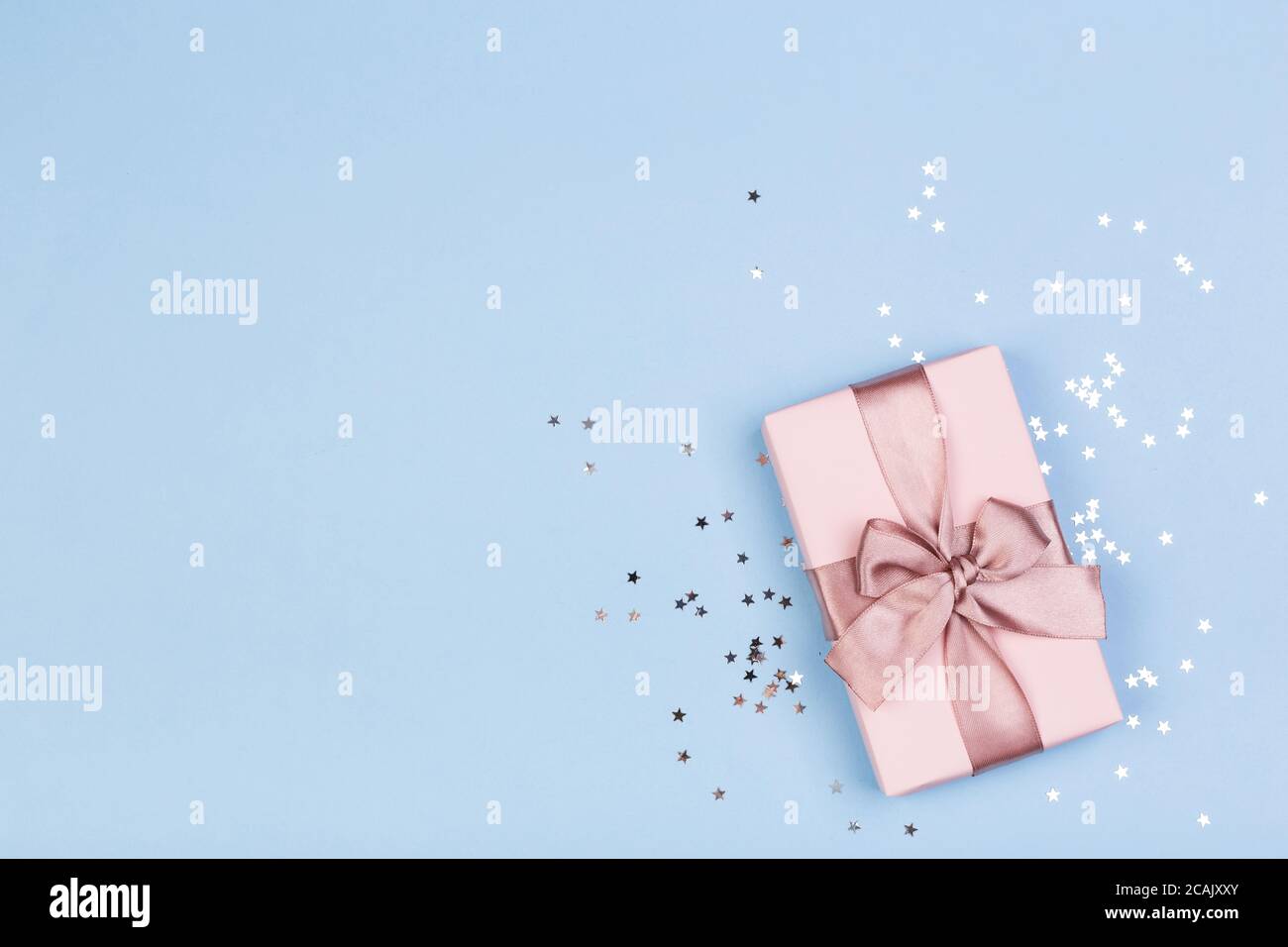 Confezione regalo o regalo e stelle confetti su un tavolo blu dall'alto. Composizione piatta per compleanno, giorno delle madri o matrimonio. Foto Stock