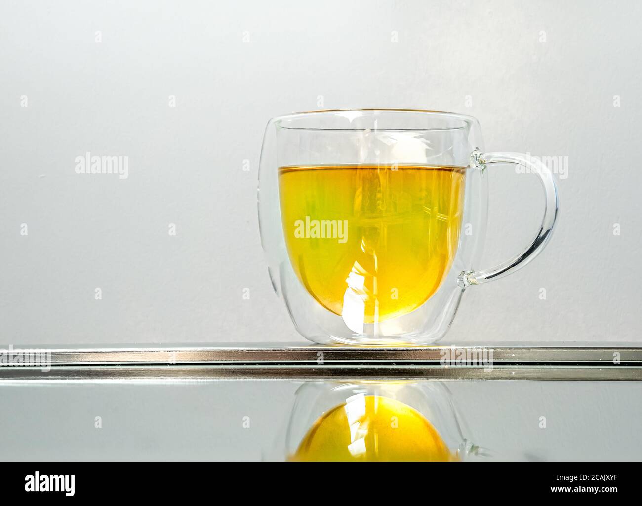 Una teiera di tè alle erbe al limone riflessa su uno specchio Foto Stock