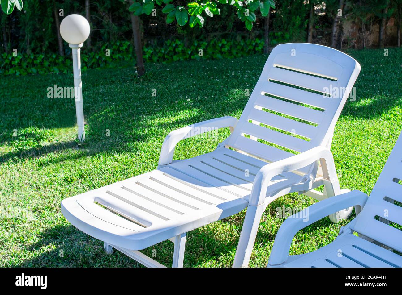 Giardino con sedie a sdraio in plastica bianca su erba tagliata di fresco  Foto stock - Alamy