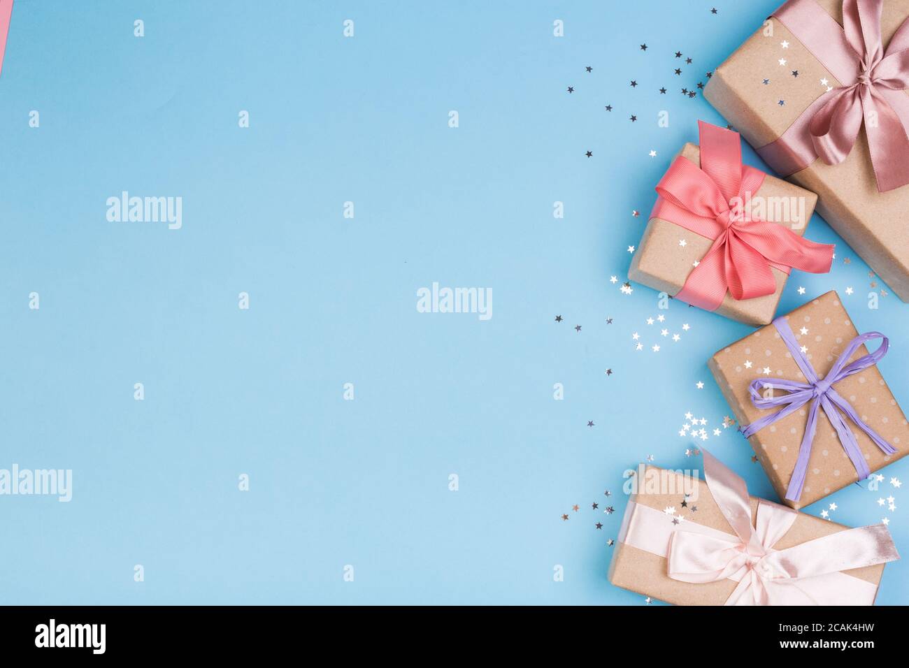 Confezione regalo o regalo e stelle confetti su un tavolo blu dall'alto. Composizione piatta per compleanno, giorno delle madri o matrimonio. Foto Stock