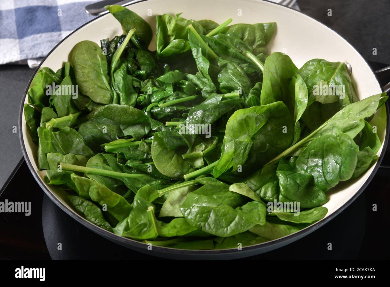 Un mazzo di spinaci saltati in una padella di ghisa per cucinare Foto Stock