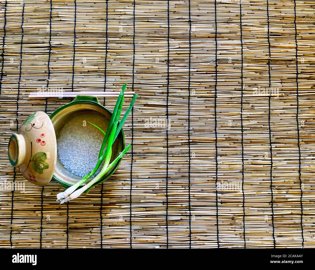 Pentola di argilla con riso e capesante su stuoia di bamboo Foto Stock