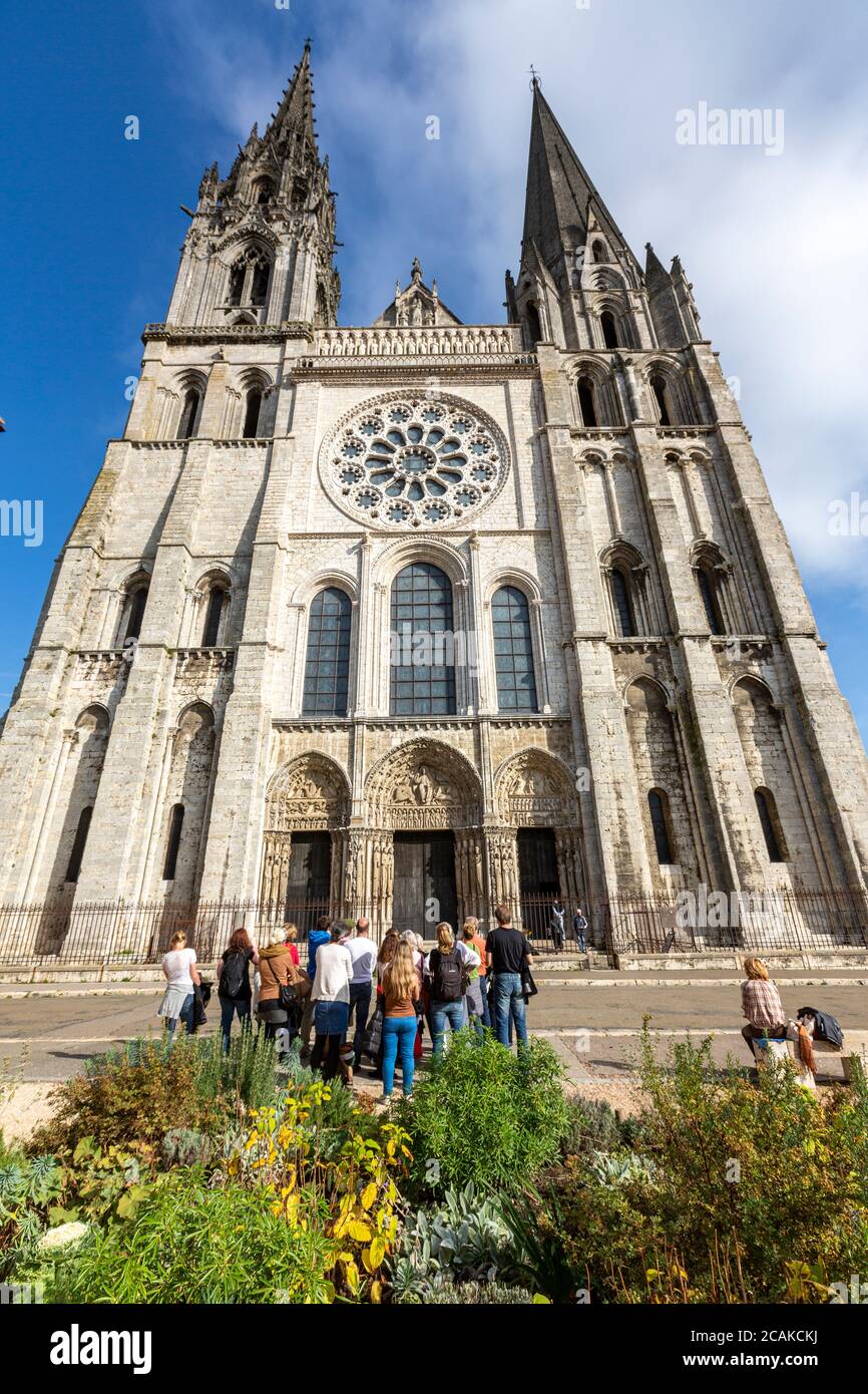 I turisti che guardano la Torre Nord Gotica (a sinistra) e la Torre Sud più vecchia sulla facciata della Cattedrale di nostra Signora di Chartres, Chartres, Francia Foto Stock