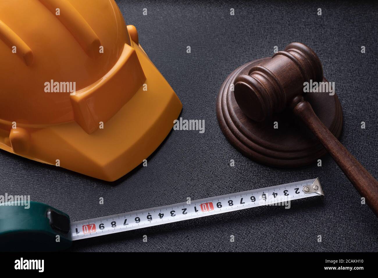 Gavel giudice in legno, casco giallo da costruzione e nastro. Concetto di legge sulla costruzione. Concetto di legge sul lavoro. Foto Stock