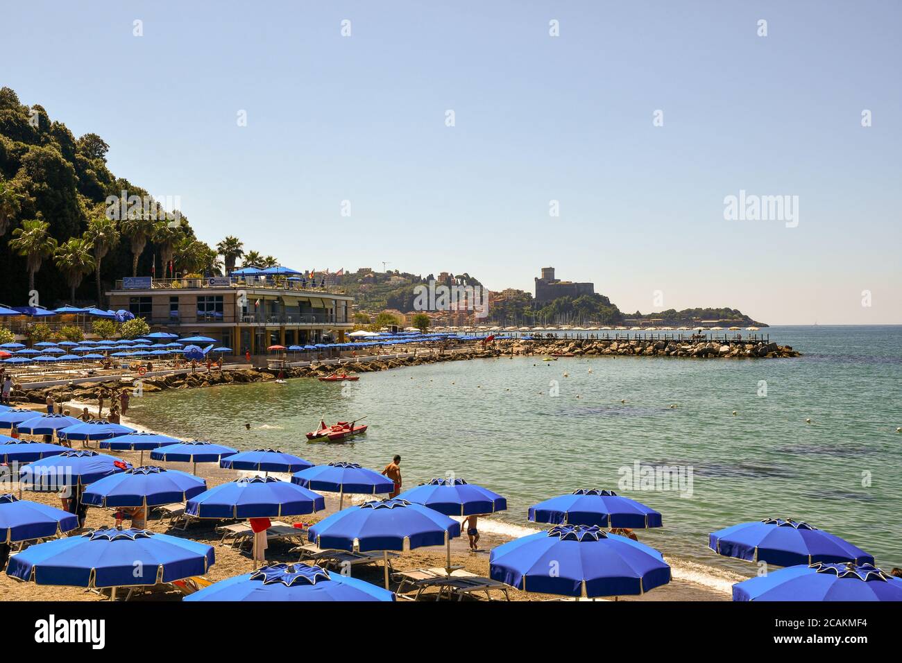 Vista panoramica sulla baia con file di ombrelloni sulla spiaggia sabbiosa e sull'antico borgo peschereccio di Lerici sullo sfondo in estate, Liguria, Italia Foto Stock