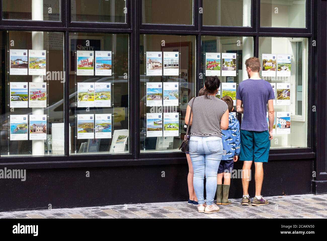 Famiglia casa di caccia cercando nella finestra agenti immobiliari Foto Stock