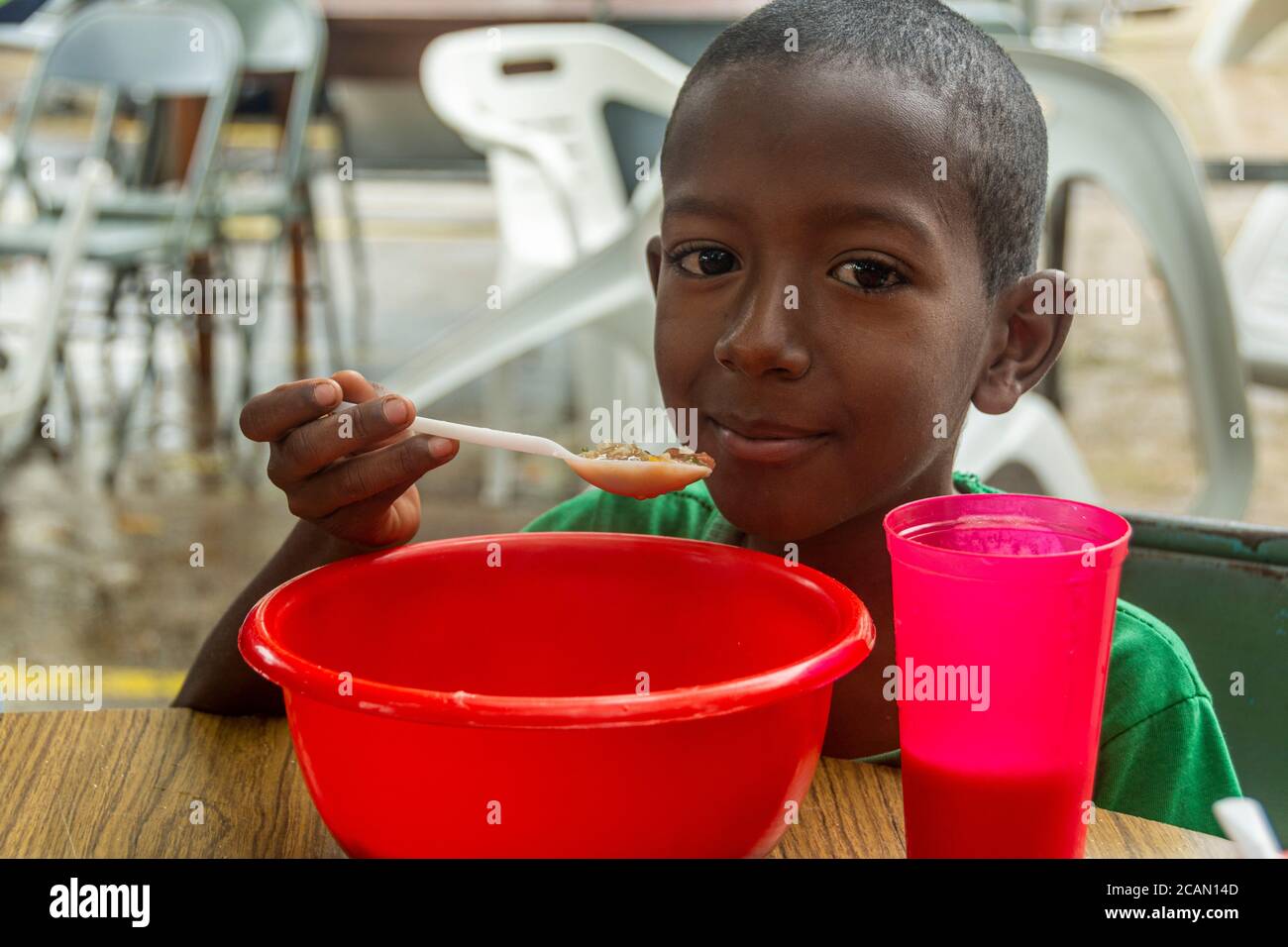 Un bambino mangia la sua zuppa a base di riso, cereali, verdure e talvolta con carne o pesce. Anche loro viene offerto un bicchiere di latte. Nella Parrocchia Maria Aux Foto Stock