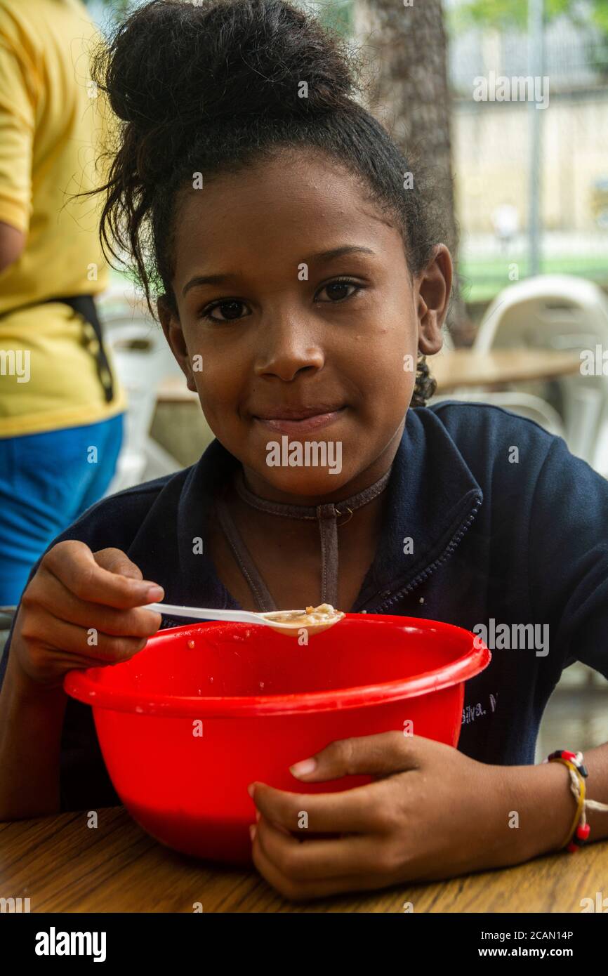 Un bambino mangia la sua zuppa a base di riso, cereali, verdure e talvolta con carne o pesce. Anche loro viene offerto un bicchiere di latte. Nella Parrocchia Maria Aux Foto Stock