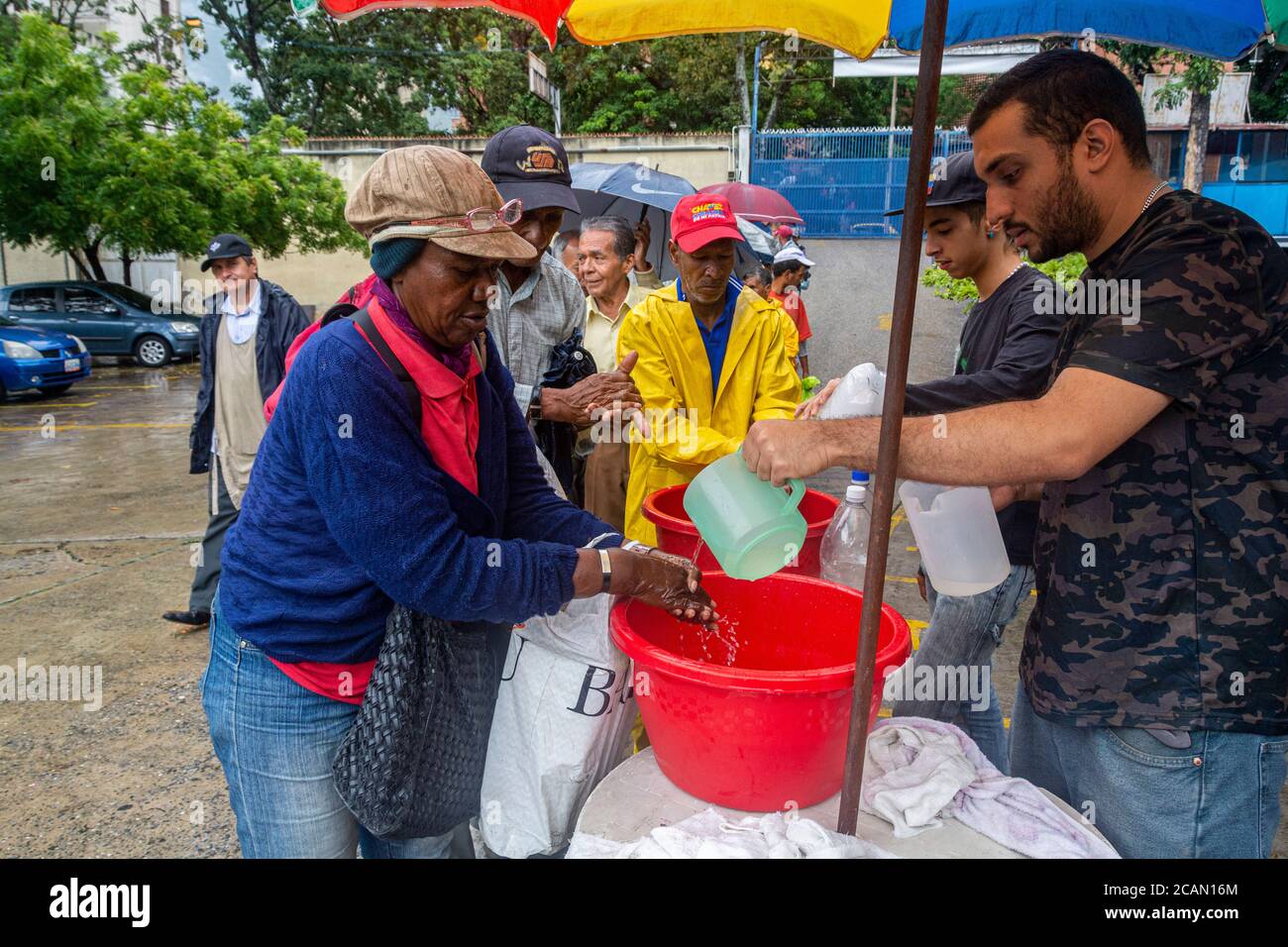 Una volta all'interno del contenitore, tutti lavano le mani per mantenere la pulizia e l'igiene. Nella parrocchia Maria Auxiliadora di Boleita, Caracas, venez Foto Stock