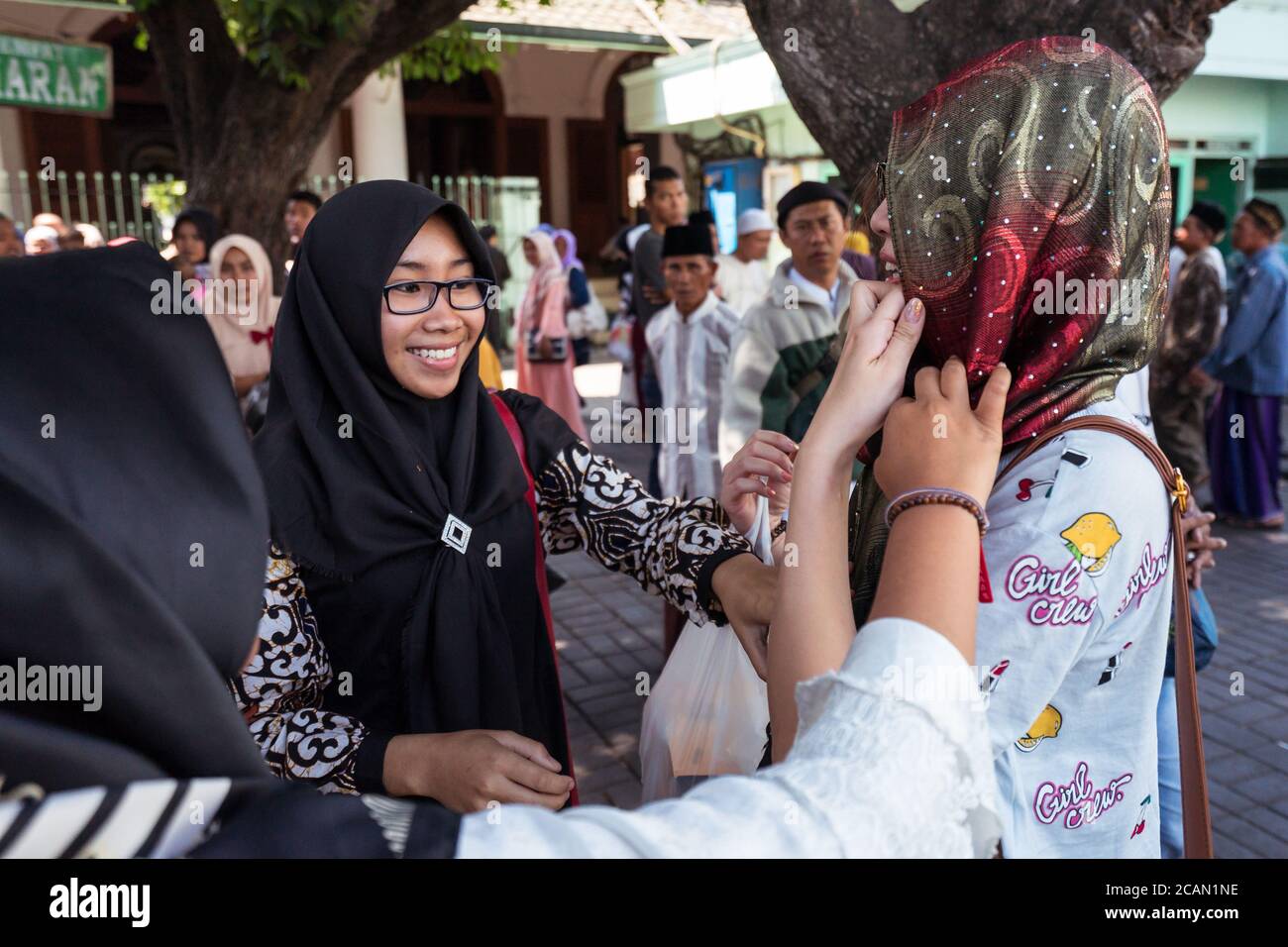 Surabaya / Indonesia - 3 agosto 2018: Giovani donne indonesiane musulmane con hijab aiutare il turista a mettere su hijab per visitare la moschea Masjid Sunan Ampel Foto Stock