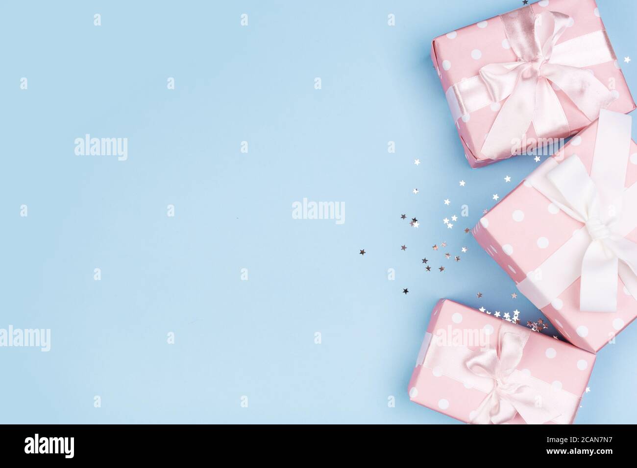 Confezione regalo o regalo e stelle confetti su un tavolo blu dall'alto. Composizione piatta per compleanno, giorno delle madri o matrimonio. Foto Stock