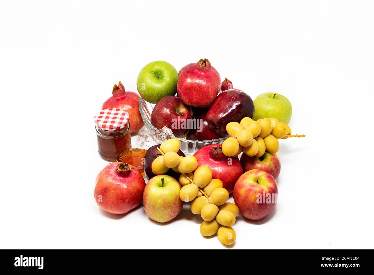 Rosh Hashanah, Capodanno ebraico, simboli tradizionali, Miele in un vaso di vetro, melograni, datteri, mele rosse e verdi. Isolato su sfondo bianco Foto Stock