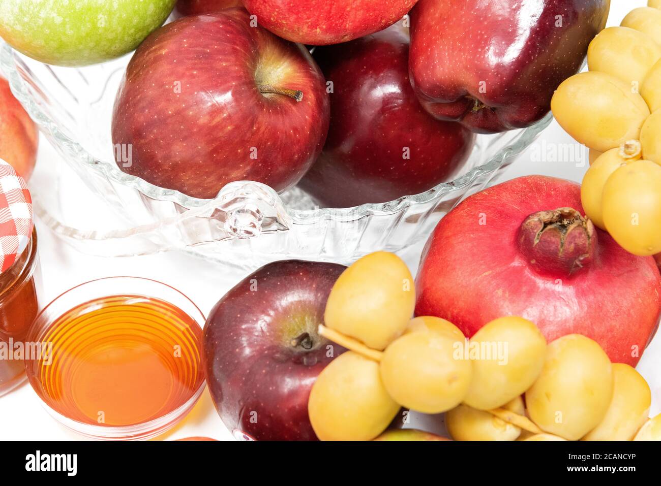 Rosh Hashanah, Capodanno ebraico, simboli tradizionali, Miele in un vaso di vetro, melograni, datteri, mele rosse e verdi. Isolato su sfondo bianco Foto Stock