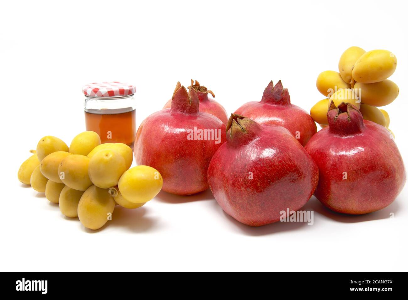 Rosh Hashanah, Capodanno ebraico, simboli tradizionali, Miele in un vaso di vetro, melograni, datteri. Isolato su sfondo bianco Foto Stock