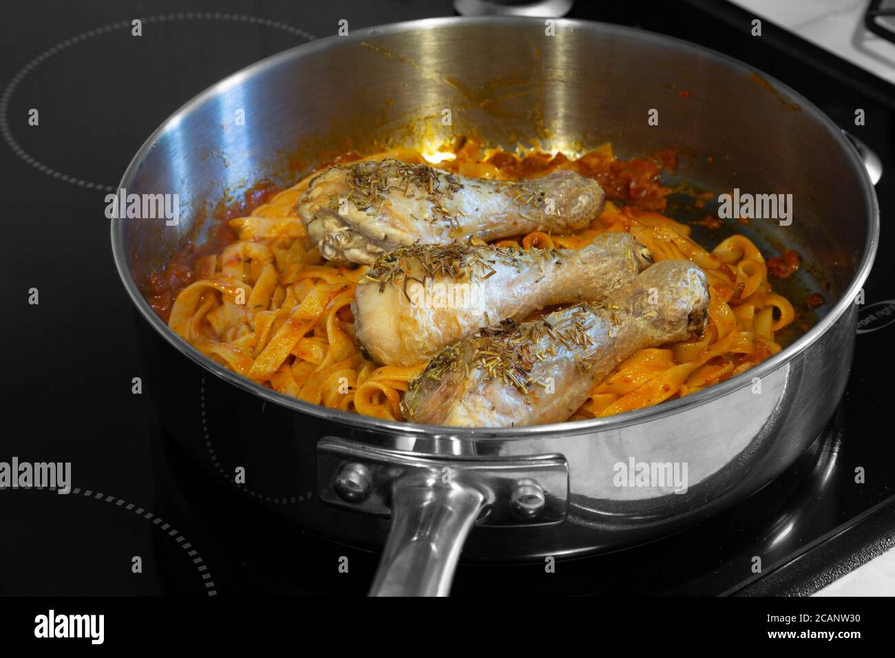 Bastoncini di pollo ricoperti di rosmarino con tagliatelle di pasta e salsa di pomodoro. Cucinare su un piano cottura in una padella. Foto Stock