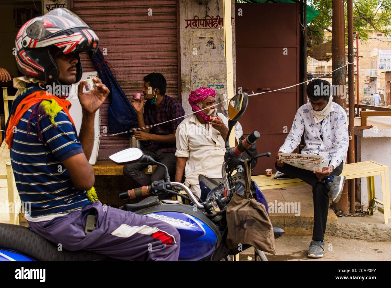 jaisalmer, rajasthan / india - luglio 22 2020 : persone che bevono chai / tè su una stalla di tè nel mezzo del mercato, uomo che beve tè su una bicicletta. Foto Stock