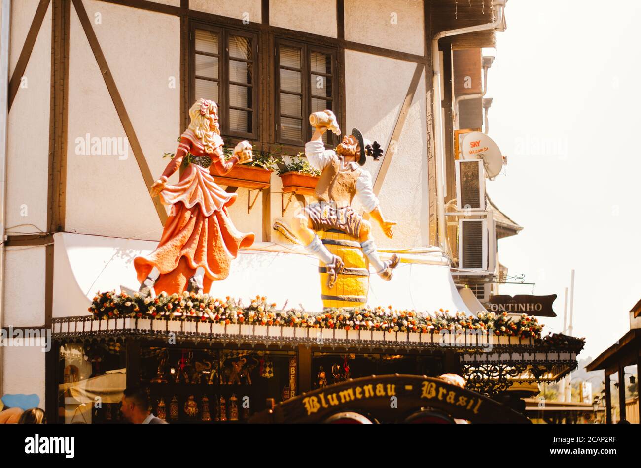 Vista frontale di una splendida casa coloniale tedesca e delle sue finestre decorate con fiori e un paio di statue tedesche bere birre a Vila Germânica, Foto Stock Vista frontale di una splendida casa coloniale tedesca e delle sue finestre decorate con fiori e un paio di statue tedesche bere birre a Vila Germânica, Foto Stock