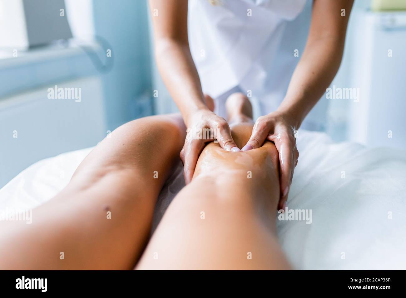 Le mani delle donne massaggiano le gambe e gli shins dell'atleta dopo la concorrenza. Massaggio sportivo, recupero. Medicina dello sport. Flebeurisma Foto Stock
