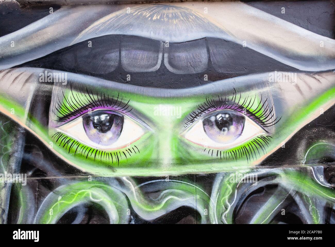 Graffiti illustrazione di ragazza occhi verdi faccia denti bocca astratta murale orizzontale sulla città edificio muro a strada percorso a piedi fatto con vernici spray stagno . Foto Stock